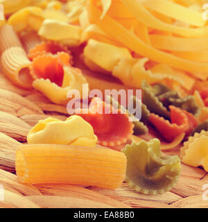 Primo piano di una pila di diverse paste alimentari non cotte come tortellini, tagliatelle o penne rigate con un effetto filtrato Foto Stock