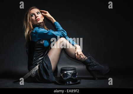 A piena lunghezza steampunk donna retrò con cilindro di studio shot grunge sfondo scuro Foto Stock