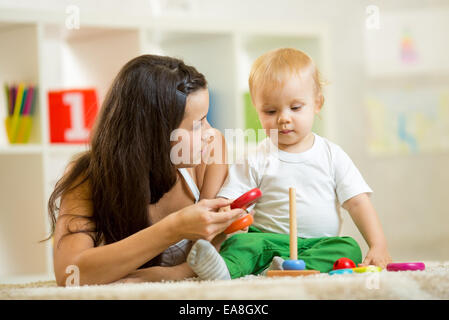 Carino madre e bambino giocare insieme indoor a casa Foto Stock