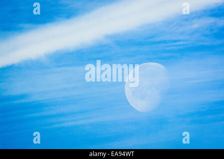 La luce diurna luna scena attraverso mattina vapore e contrails. Foto Stock