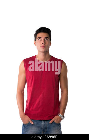 Attraente giovane uomo in rosso maglia senza maniche e jeans, guardando in alto, isolato su bianco Foto Stock