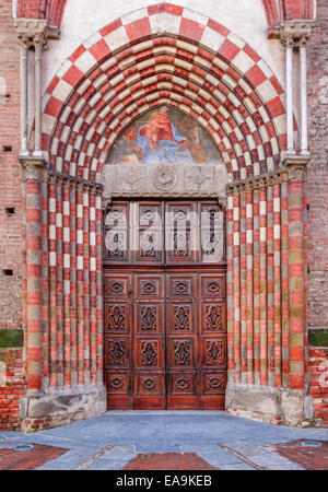 Vintage vecchia porta di legno all'ingresso alla chiesa cattolica di Alba, Italia (composizione verticale). Foto Stock