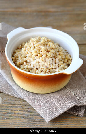 Bollito di orzo perlato in marrone ceramica pentola, cibo sano Foto Stock