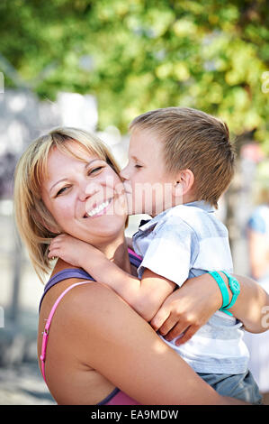 Little Boy bacia la sua felice madre sulla natura Foto Stock