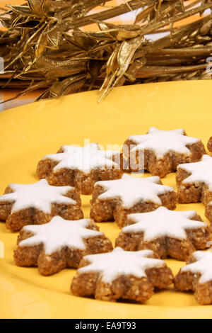 La cannella star cookies (in tedesco Zimtsterne) sono tipici tedeschi e svizzeri biscotti di Natale fatto di mandorle. Al di sopra di una piastra di colore giallo Foto Stock