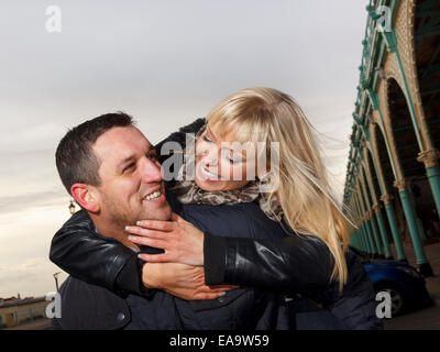 Un giovane godendo una giornata nella località balneare inglese a Brighton in caldo abbigliamento invernale Foto Stock