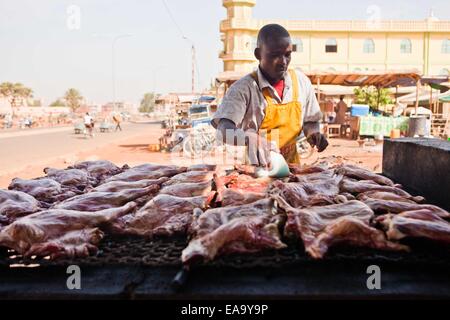 (141110) -- OUAGADOUGOU, nov. 10, 2014. (Xinhua) -- Un hawker cuochi arrosti di carni di montone gambe a Ouagadougou, capitale del Burkina Faso, nov. 10, 2014. (Xinhua/Li Jing) Foto Stock