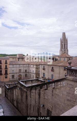 Vista panoramica di uno storico paesaggio urbano spagnolo con edifici in pietra, torre della chiesa, terrazze e montagne lontane sotto un cielo nuvoloso Foto Stock