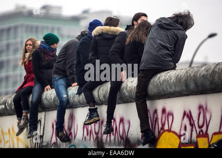 Berlino, Germania. 09Nov, 2014. I giovani seduti sul muro di Berlino presso la East Side Gallery in occasione del XXV anniversario della caduta del muro di Berlino a Berlino, Germania, 09 novembre 2014. Foto: Maja Hitij/dpa/Alamy Live News Foto Stock