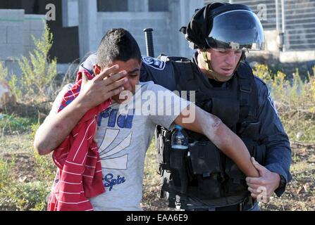 Gerusalemme. 9 Nov, 2014. Un poliziotto detiene un arabo israeliano la gioventù a Kfar Kanna villaggio nel nord di Israele nov. 9, 2014. Scontri scoppiati tra arabi e polizia dopo poliziotti israeliani ucciso un arabo israeliano l uomo al villaggio di notte di venerdì. Credito: JINI/Xinhua/Alamy Live News Foto Stock