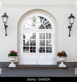 Un elegante stile classico doppia vetrata in vetro porta anteriore con lanterne anteriore e vasi di fiori Foto Stock