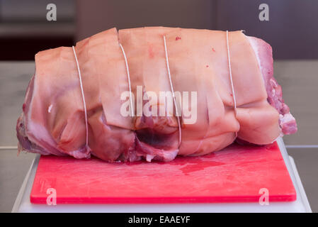 Unendo la carne di maiale su un tagliere rosso di carne cruda Foto Stock