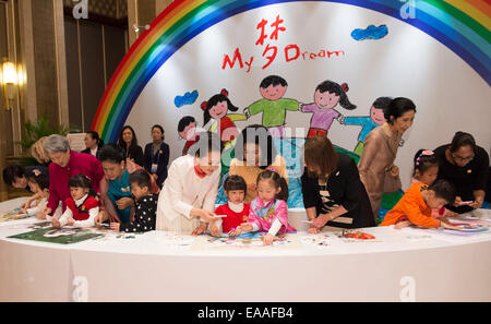 (141110) -- PECHINO, nov. 10, 2014 (Xinhua) -- Peng Liyuan (in abito bianco), la moglie del Presidente cinese Xi Jinping, giochi puzzle con i bambini con disabilità uditiva insieme con i coniugi di alcuni leader della Cooperazione economica Asia-Pacifico (APEC) le economie dei paesi membri durante un'attività incentrata sulle questioni di sviluppo riguardanti i disabili, a Pechino, Cina, nov. 10, 2014. (Xinhua/Huang Jingwen)(hdt) Foto Stock