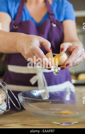 Una donna a un tavolo da cucina fata di cottura per torte. Foto Stock