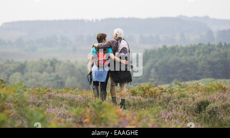 Un paio di piedi su un percorso guardando la vista sulle colline boscose, con bracci intorno all'altro. Foto Stock