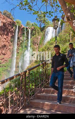 Vista verticale delle persone che camminano giù i passaggi presso Cascades d'Ouzoud in una giornata di sole. Foto Stock