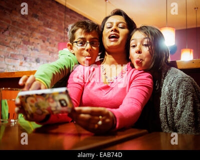 Donna assume selfie sul telefono. Figlia di madre e figlio. Foto Stock