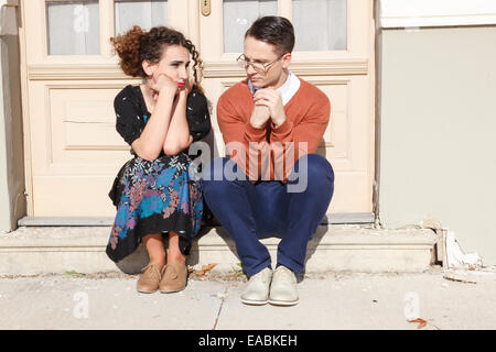 Premuto e agitato l uomo e la donna accovacciata davanti alla casa di scale a causa problema hanno, triste emozioni Foto Stock