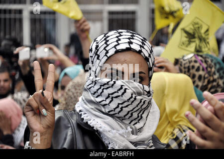 La città di Gaza, Striscia di Gaza, Territori palestinesi. Xi Nov, 2014. Una femmina di sostenitore dei Palestinesi movimento Fatah lampeggia in segno di vittoria nel corso di una manifestazione che segna il decimo anniversario della fine il leader palestinese e il fondatore del movimento di Yasser Arafat di fronte al Al-Azhar University di Gaza City, il 11 novembre 2014 Credit: Mohammed Talatene APA/images/ZUMA filo/Alamy Live News Foto Stock