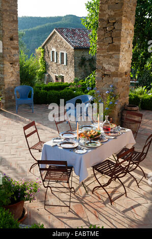 La tabella prevista per il pasto sul patio coperto di agriturismo nelle colline umbre Foto Stock