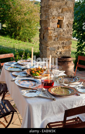 Vivacemente colorato sulle piastre outdoor tavolo da pranzo con le vecchie sedie in ferro Foto Stock