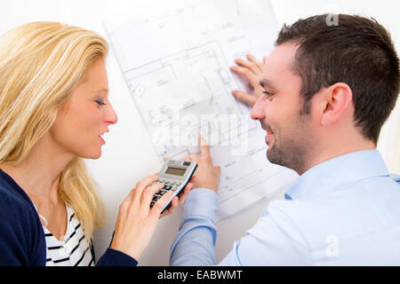 Vista di una giovane coppia studiando piani della loro futura casa Foto Stock