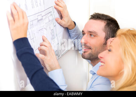 Vista di una giovane coppia studiando piani della loro futura casa Foto Stock