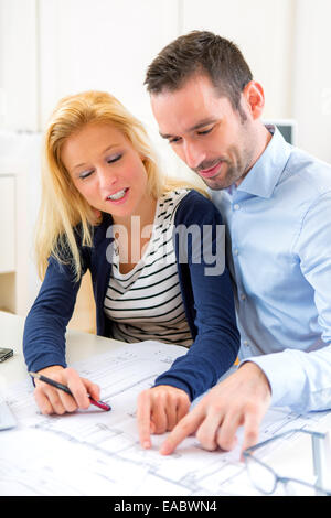 Vista di una giovane coppia studiando piani della loro futura casa Foto Stock