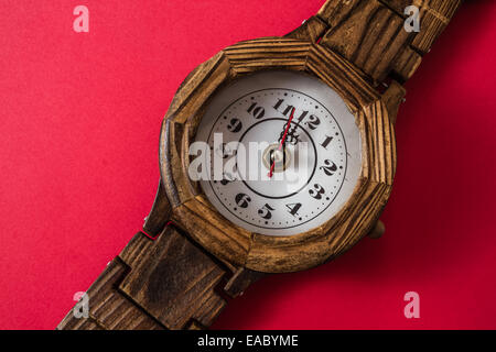 Fatto a mano in legno Orologio a parete su uno sfondo rosso Foto Stock
