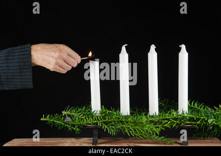 Illuminazione il primo avvento candela con una partita a uno sfondo nero Foto Stock