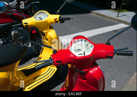 Giallo e rosso Vespa Piaggios parcheggiato a fianco a fianco. Foto Stock
