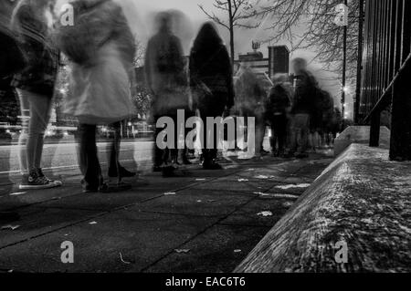 Lunga coda di adolescenti in attesa su una strada di città in bianco e nero Foto Stock