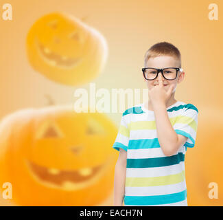 Ragazzo sorridente in bicchieri su sfondo di zucca Foto Stock