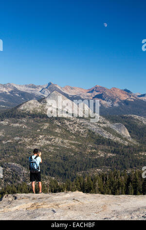 Un uomo che cammina su Sentinel Dome in Yosemite National Park, California, USA, guardando ad est al Pacific Crest Trail montagne. Foto Stock