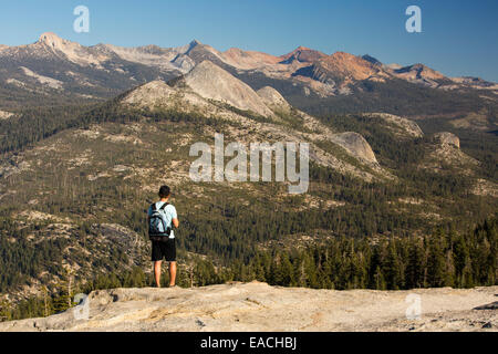 Un uomo che cammina su Sentinel Dome in Yosemite National Park, California, USA, guardando ad est al Pacific Crest Trail montagne. Foto Stock