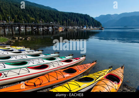 Kayaks colorati sono allineati sulla spiaggia di Baia profonda di Canoa e Kayak Center. Deep Cove, N Vancouver Foto Stock