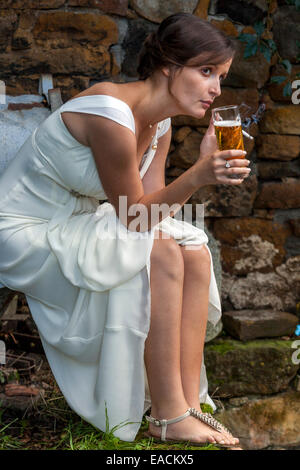 Sposa che riposa donna sola che beve birra che fuma una sigaretta Foto Stock