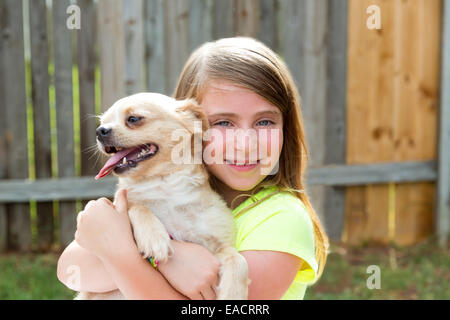 Bionda ragazza di capretto con chihuahua cane giocare felici all'aperto Foto Stock