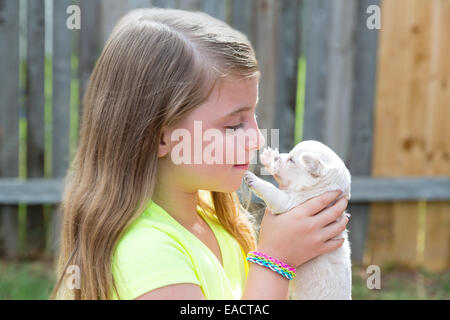 Bionda ragazza di capretto con cucciolo pet chihuahua giocando felice con doggy outdoor Foto Stock