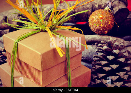 Alcune confezioni regalo legato con rafia naturale di diversi colori con le palle di Natale, pigne nelle quali i registri e in background Foto Stock