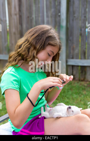 Kid ragazza di scattare le foto di cucciolo di cane pet con fotocamera nel cortile esterno Foto Stock