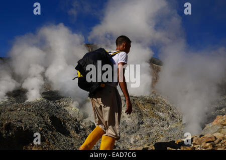 Un uomo che cammina su un sentiero di montagna, in uno sfondo del cratere vulcanico del vulcano Papandayan a Garut, Giava Occidentale, Indonesia. Foto Stock