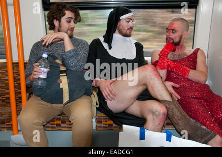 London Overground. Post Halloween party frequentatori uno in una suora è abitudine, un altro in un abito rosso di ritorno a casa dopo una festa Foto Stock