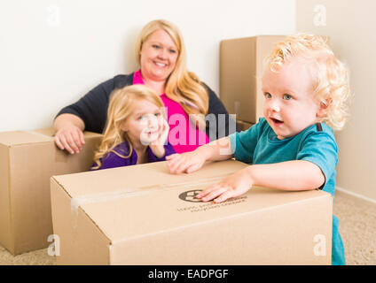 Giocoso giovane famiglia nella stanza vuota a giocare con le caselle in movimento. Foto Stock