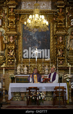 Sacerdote celebrare la Messa cattolica di fronte all'altare della chiesa Foto Stock