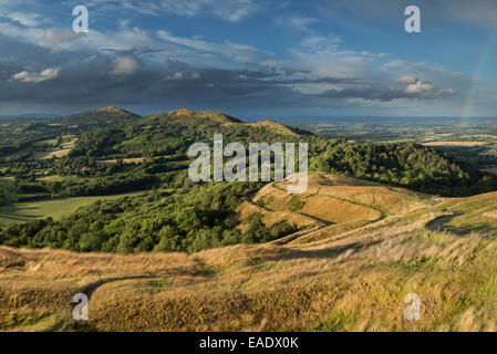 La bastionata di British Camp, Herefordshire sono illuminati dal sole al tramonto mentre la pioggia nuvole si raccolgono al di sopra della Malvern Hills Foto Stock
