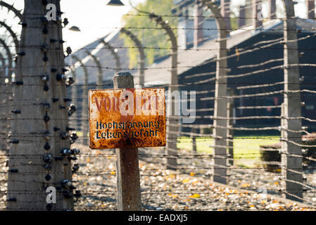 AUSCHWITZ, Polonia - 25 ottobre 2014: un segnale di avviso nella parte anteriore di un recinto elettrico nel campo di concentramento di Auschwitz Foto Stock