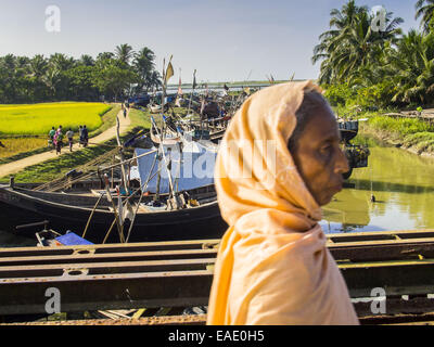 Sittwe, Rakhine, Myanmar. 9 Nov, 2014. Un Rohingya donna musulmana attraversa un ponte in un musulmano Rohingya IDP camp nei pressi di Sittwe. Dopo la violenza settaria devastato Rohingya europee e ha lasciato centinaia di Rohingya morto nel 2012, il governo di Myanmar costretto più di 140.000 Rohingya musulmani che vivevano in ed intorno a Sittwe, Myanmar, nella squallida degli sfollati interni camps. Il governo dice che i Rohingya non sono cittadini birmani che sono immigrati illegali dal Bangladesh. Il governo del Bangladesh dice i Rohingya sono e birmani Rohingya insistere sul fatto che essi hanno live Foto Stock