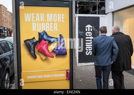 Due uomini a piedi passato colorato di un annuncio pubblicitario per scarpe di gomma. Foto Stock