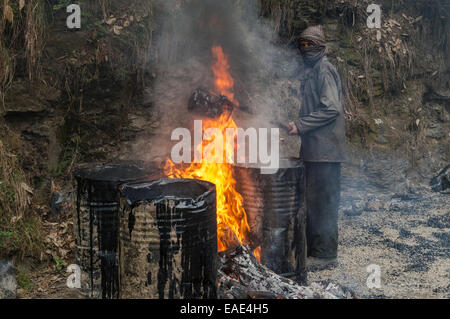 Un lavoratore di catrame di riscaldamento in barili con un fuoco aperto in corrispondenza di una strada in costruzione sito, Shimla, Himachal Pradesh, India Foto Stock